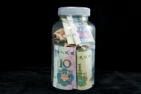 Renminbi banknotes inside glass jar on black backgroundの写真素材