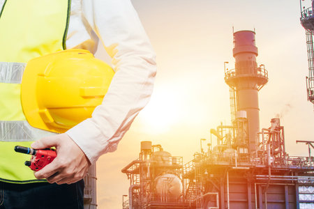 Engineering man standing with white safety helmet against oil refinery in petrochemical Aerial view...