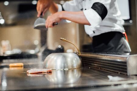 Hand of man take cooking of meat with vegetable grill, Chef cooking wagyu beef in Japanese teppanyaki restaurantの写真素材