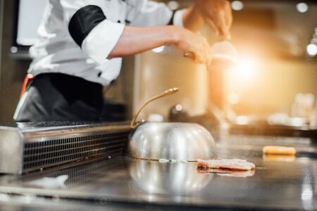 Hand of man take cooking of meat with vegetable grill, Chef cooking wagyu beef in Japanese teppanyaki restaurantの写真素材
