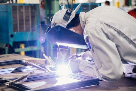 Industrial worker in manufacturing plant grinding to finish a Metal pipe,Industrial Worker at the factory welding closeupの写真素材