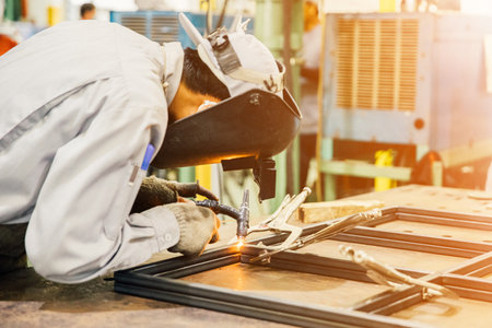 Industrial worker in manufacturing plant grinding to finish a Metal pipe,Industrial Worker at the factory welding closeupの写真素材
