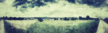 panoramic view over green with dark clouds in vintage lookの写真素材