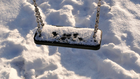 swing with snow cover in wintertimeの写真素材