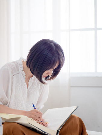 Beautiful woman reading a book in morningの写真素材