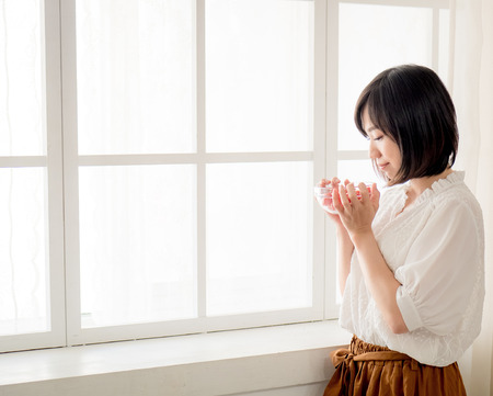 Woman having breakfast on windowの写真素材