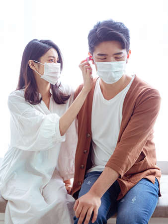 Young asian couple wearing surgical mask and using Ear thermometerの写真素材