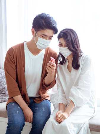 Young asian couple wearing surgical mask and using Ear thermometerの写真素材