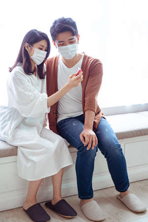 Young asian couple wearing surgical mask and using Ear thermometerの写真素材