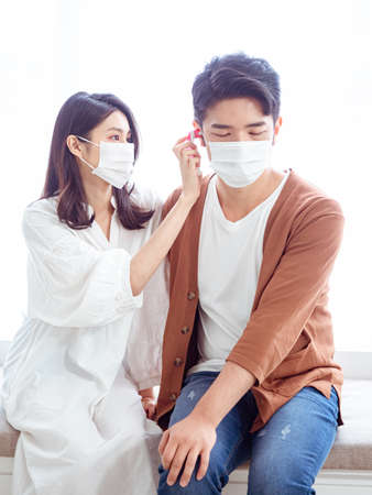 Young asian couple wearing surgical mask and using Ear thermometerの写真素材