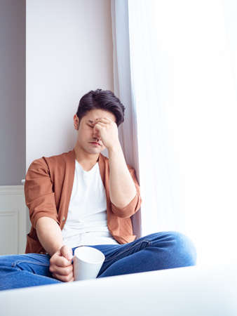 Young Asian man wearing casual clothes and having a headacheの写真素材