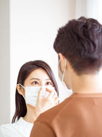 Young asian woman and man wearing Surgical mask at homeの写真素材