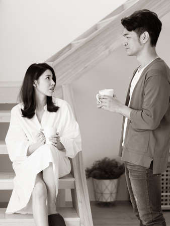 Young asian woman and man at home with cup of coffee in hands in black and white.の写真素材