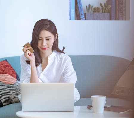 Young asian beauty shopping online with credit card and laptop at homeの写真素材
