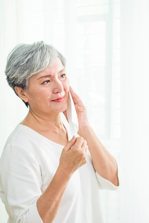 Asian senior woman wearing facemask during  flu outbreak. Virus and illness protection, home quarantine.の写真素材
