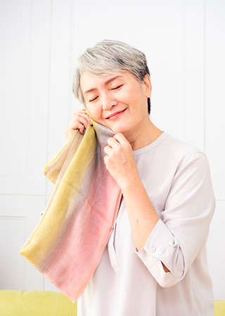 Senior Asian woman receives scarf at home.の写真素材