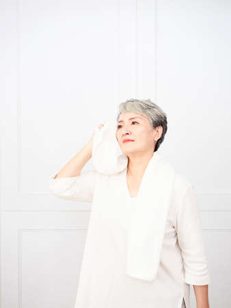 Active mature female refreshing and wipe sweat during workout.の写真素材