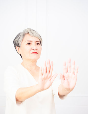 Senior beautiful grey-haired woman wearing casual dress doing stop sign with palm of the hand. Warning expression with negative and serious gesture on the face.の写真素材