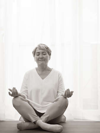 Senior asian woman doing sports at home on a Mat, healthy lifestyle concept.の写真素材