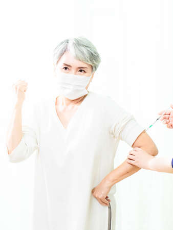 Senior asian woman receiving the injection of the  vaccine by a doctor to receive the antibodies, immunize the population.の写真素材