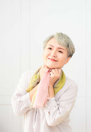 Senior beautiful grey-haired asian woman wearing casual dress and silk scarf.の写真素材