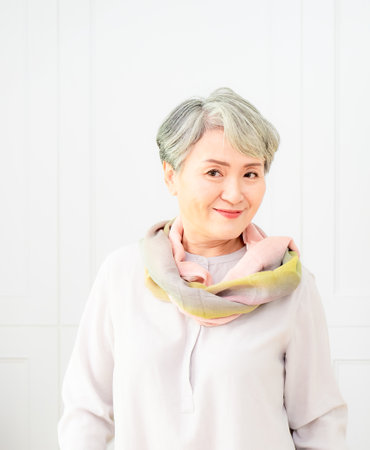 Senior beautiful grey-haired asian woman wearing casual dress and silk scarf.の写真素材