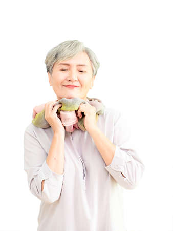 Senior beautiful grey-haired asian woman wearing casual dress and silk scarf against blank copyspace wall background.の写真素材