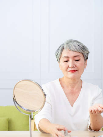 Senior Asia woman is spraying perfume at home.の写真素材