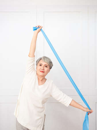Senior asian woman doing exercises with resistance band at home.の写真素材