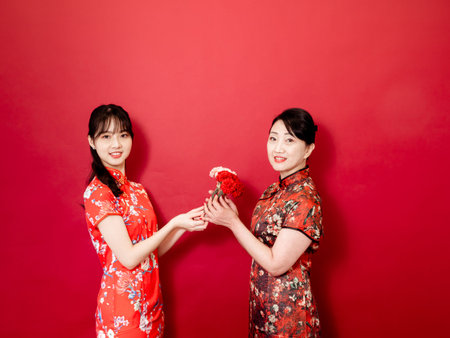 Portrait of asian young daughter and mother wearing traditional cheongsam qipao and smiling with...