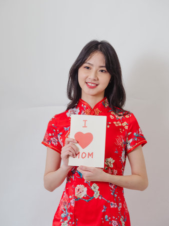 Portrait of a young asian woman wearing traditional cheongsam qipao dress holding handmade Greeting...