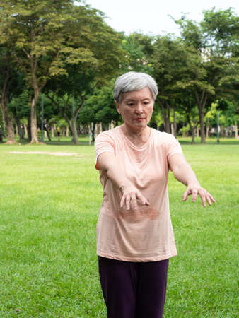 Portrait of happy senior adult elderly asia woman smiling standing and stretch her arms relax and enjoy with nature fresh air in the park.の写真素材