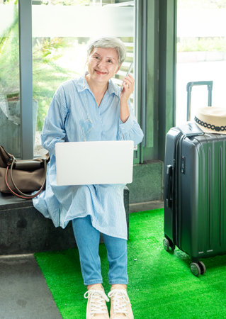 relax, vacation, travel, portrait of senior adult elderly asian woman 60s smiling using the computer laptop and smartphone while waiting for their travel time.の写真素材