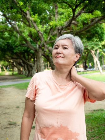 Portrait of mature asian woman 60s with shoulder pain at park outdoor.の写真素材