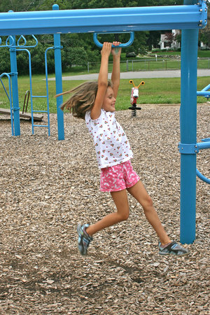 a little girl sliding on a bar in a park