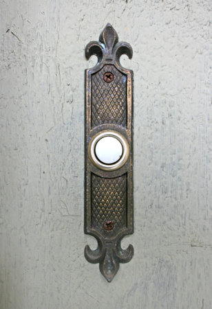 An ornate electric doorbell on painted woodの写真素材