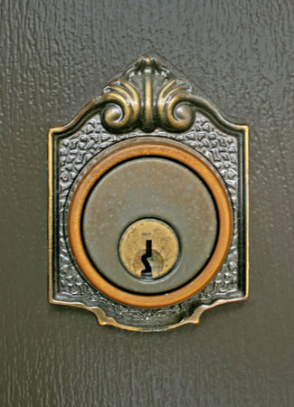 an ornate brass keyhole on painted woodの写真素材