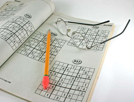 newspaper puzzles, eyeglasses and pencil on an isolated backgroundの写真素材