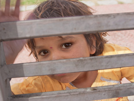 little girl looking through a gate - Delhi, Indiaのeditorial素材