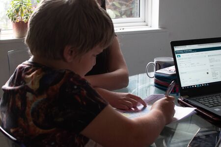 Two school age children, 13 and 8 helping each other with their homeworkの写真素材