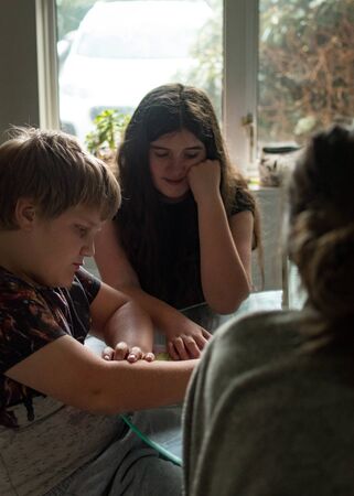 Two school age children, 13 and 8 helping each other with their homeworkの写真素材