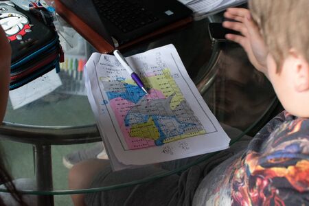 Two school age children, 13 and 8 helping each other with their homeworkの写真素材