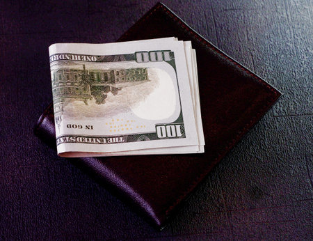 American dollar bills lying on a leather wallet.