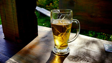 Glass of beer on a wooden table in a summer cafe in the village