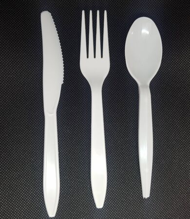 White plastic cutlery on a black background, knife, fork and spoonの写真素材
