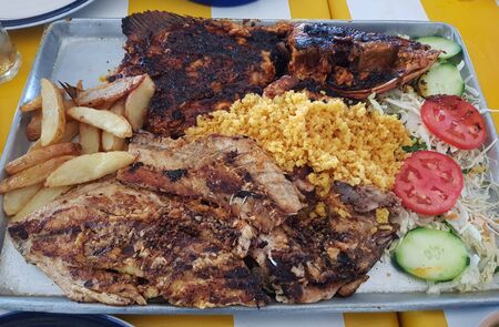 Grilled fish fillets served with yellow rice, salad and potatoes, restaurantの写真素材