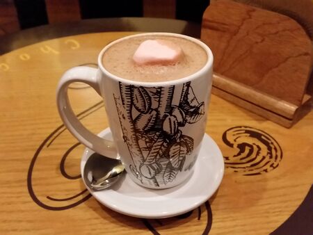Cup of hot chocolate on wooden table with a marshmallow, restaurantの写真素材