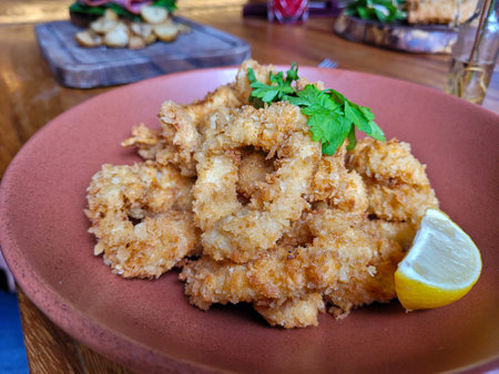 Delicious golden-brown breaded calamari served with a fresh lemon wedge, Restaurantの写真素材