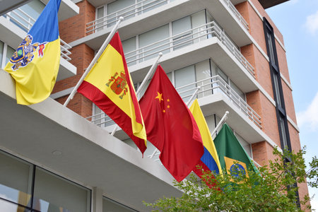 A row of flags from different countries are hanging from the side of a building.の写真素材