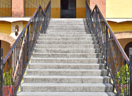 A set of stairs with a wrought iron railing in Saint John The Evangelist town. The stairs are made of concrete and are very tallの写真素材